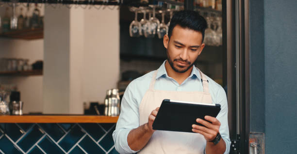 istock Asian man, waiter and tablet or restaurant for service or online booking with customer help, small business or cafe. Male person, apron and mobile app for contact us or reading, sales or hospitality 2154114057