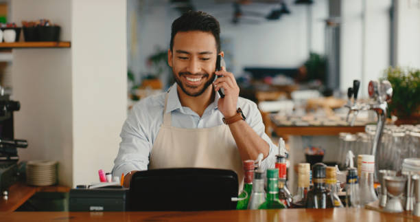 istock Business, waiter or phone call at counter in cafe for order, customer support or talking for takeaway. Professional, man or smartphone in coffee shop with online management, digital sale or ecommerce 2154115210