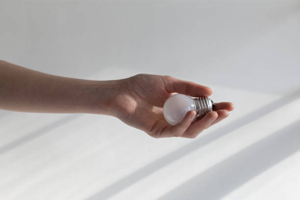 istock energy saving light bulb in female hand on white background 2154118794