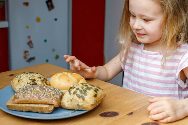 istock girl and bread rolls on the table for breakfast. 2154119226