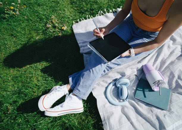 istock Young woman using digital tablet and stylus in a park 2154121922