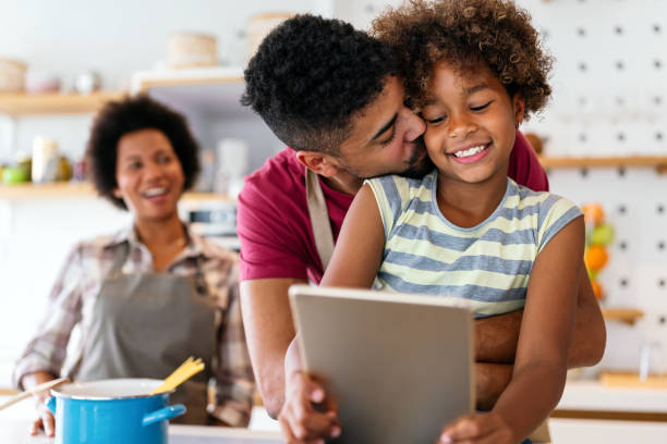 istock Happy african family having fun with device at home, using digital tablet looking at screen together 2154121966