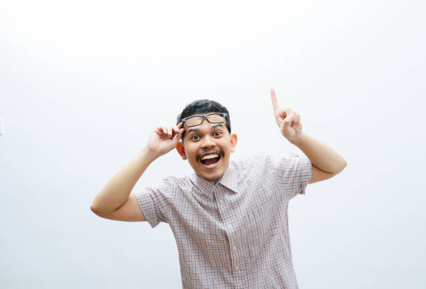 an asian man smiles and points to something with his hand