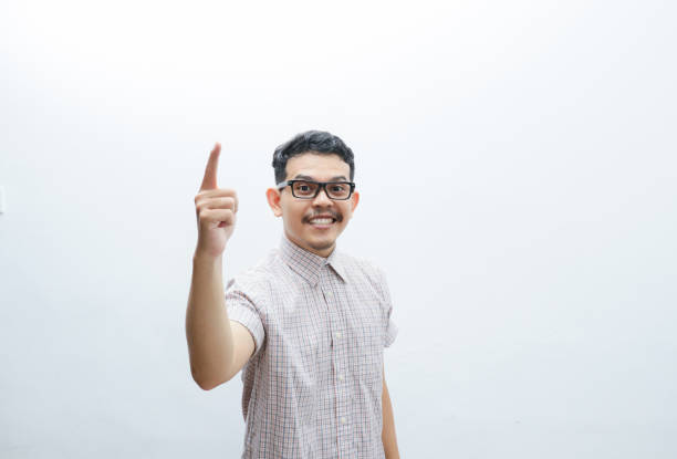 an asian man smiles and points to something with his hand