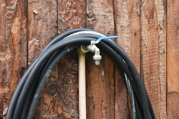Water tap with metal garden hose adapter closeup on green grass background