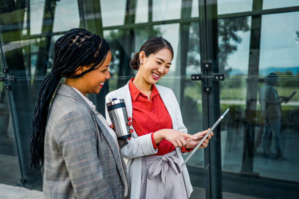 istock Two diverse female coworkers using tablet outdoors 2154129645