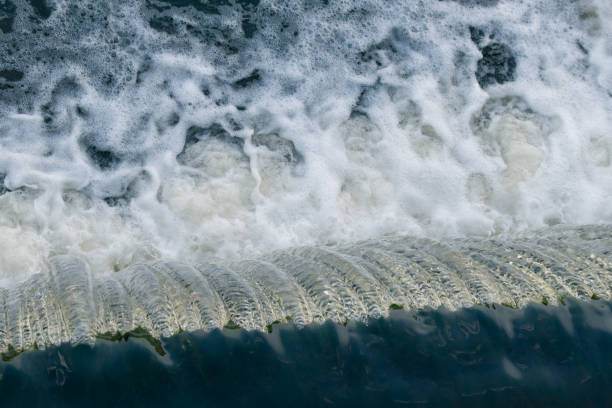 Streams of water fall from a water dam. Water foam. Waterfall.