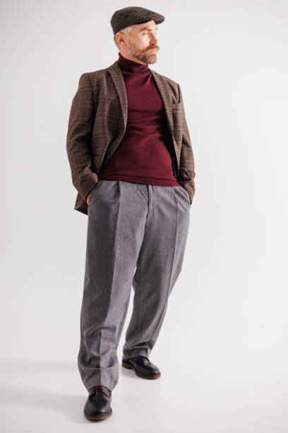 istock Bearded man in plaid flat cap and jacket posing on gray background 2154131952