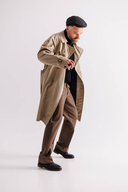 istock Stylish and elegant man in flat cap and trench coat dancing on grey background 2154131992