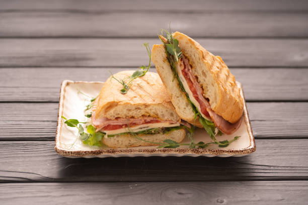 istock Grilled and pressed bread with smoked ham, cheese, tomato and lettuce served on plate. 2154133723