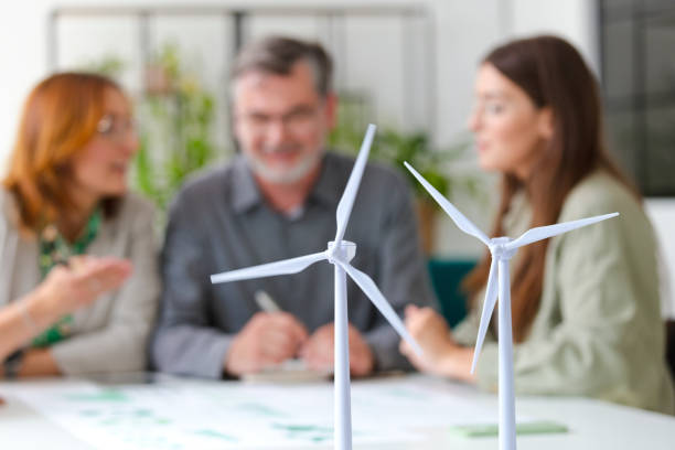 istock Wind turbine models against colleagues discussing in office 2154134459
