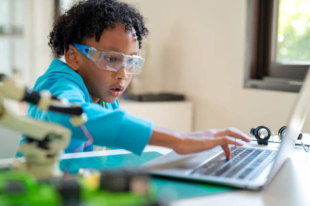 istock African boy wearing safety glasses is focused and concentrated as he uses a computer to write coded instructions for a robot to move. Child's engagement in e-learning and STEM topics. 2154134672
