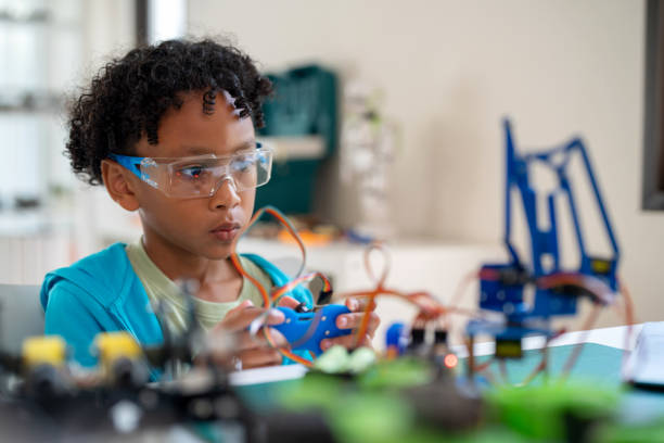 istock A young black child is deeply engaged in writing coding to control a mechanical arm in his living room. Engaging in online e-learning with expert teachers, the child demonstrates curiosity, creativity, and a passion for STEM topics. 2154136058