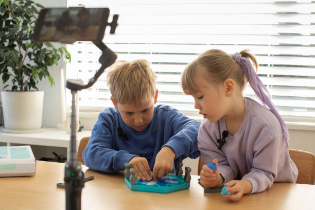 istock Kids play a new board game for their blog, recording a fun and interactive game session 2154136382