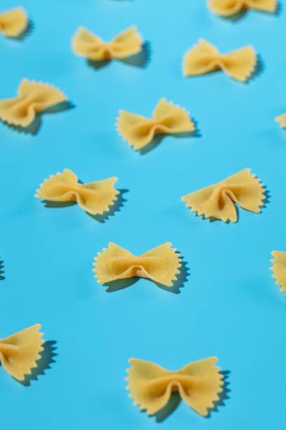 istock Uncooked bow tie pasta, farfalle scattered on a blue background in a decorative pattern 2154136483
