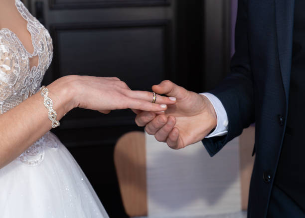 istock The groom puts a wedding ring on the bride's finger. Without a face 2154136799