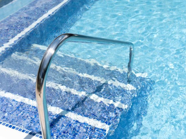 istock Shiny Metal Pool Ladder in Clear Blue Water 2154138260