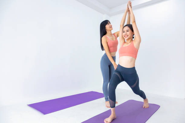 istock Asian women practicing sun salutation yoga indoor with her class trainer leg stretching position to control breathing in and out for good health 2154140156