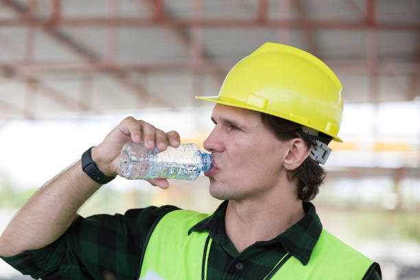 istock Male engineer drinking water at construction site. Male construction builder drinking water at site work 2154150262