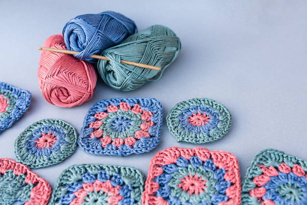 istock Crochet hook, inserted in skeins of smooth yarn with granny squares around. 2154156480