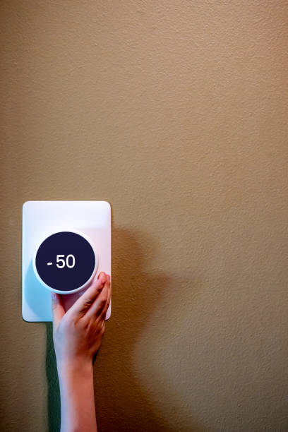 istock Small child hand reaching up to change the temperature on a thermostat. 2154158004