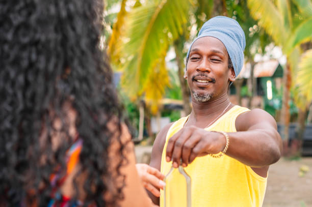 Image of a black man with Chinese eyes giving something to a Latina girl. Multi ethnic man smiling at curly haired girl.