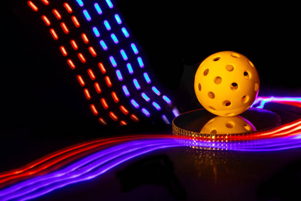 Abstract yellow Pickleball with colorful lighting and black background.