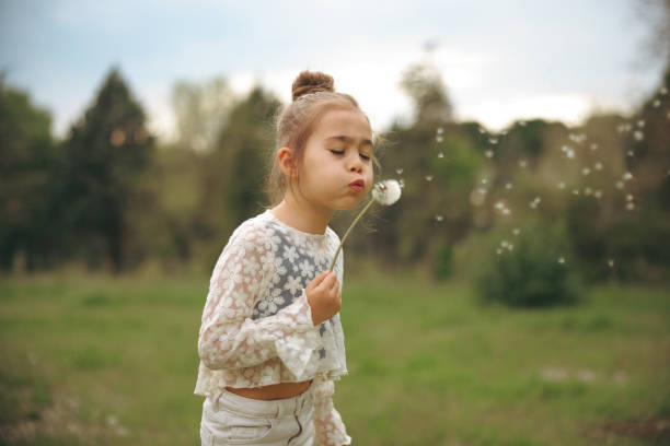 istock Happy girl blowing dandelion 2154167528