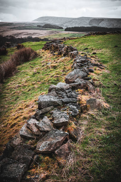 istock Scenic hillside with a long weathered stone wall, distant mountains under a cloudy sky, highlighting natural beauty and tranquil wilderness. 2154169643