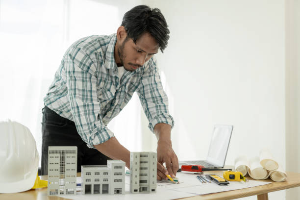 istock Architects studying floor plans, serious civil engineers working with documents on real estate construction, and professional foremen in home improvement: 2154173781
