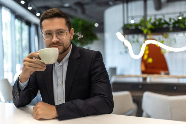 istock Smiling businessman drinking coffee in cafe and looking looking at camera 2154180769