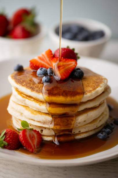 istock pouring syrup on piled pancake with strawberries and bluberries 2154182606