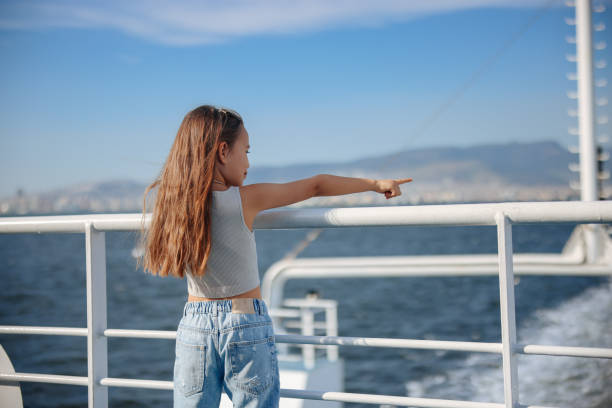Little girl is on a ship, boat or ferry. Little girl learning out of the stern of a ship. ferry deck girls stock pictures, royalty-free photos & images