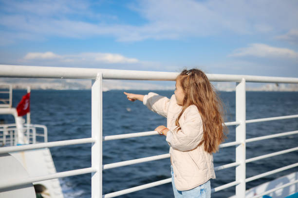 Little girl is on a ship, boat or ferry. Little girl learning out of the stern of a ship. ferry deck girls stock pictures, royalty-free photos & images