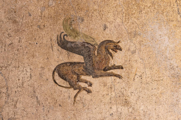 Fresco showing winged creature; probably a griffin. The Pompeians used the griffin in their murals, but this mythical creature goes back thousands of years, to India, Assyria and Persia. The creature is basically the combination of an eagle and a lion. The head and front of the body — including the front legs and wings — are represented by an eagle. In addition, the eagle head features long ears that are sometimes feathered. The rest of the body belongs to a lion. Altogether, the creature symbolizes strength and wisdom. Because the griffin traditionally guards treasure, he also symbolizes vengeance.\nDomus P. Cornelius Tages\nor House of the Ephebus