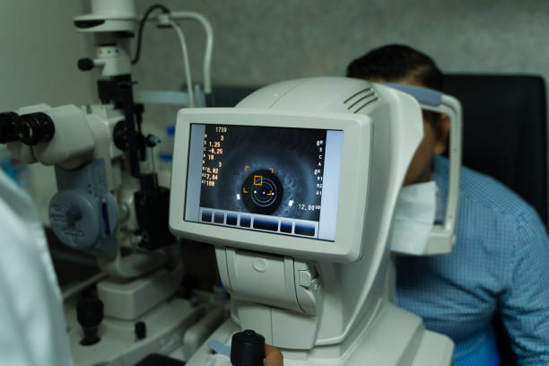 Professional ophthalmologist is using advanced diagnostic equipment to perform a comprehensive eye exam on a seated patient in a clinic
