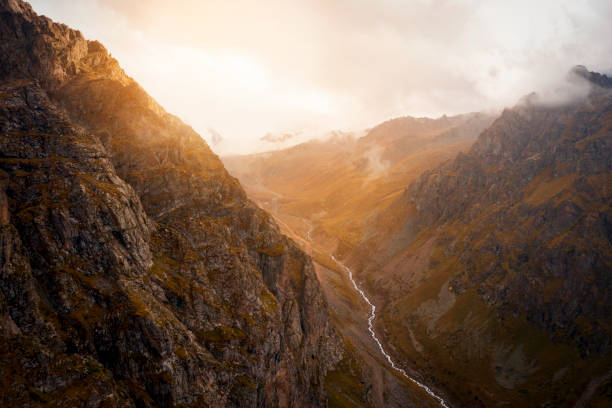 Young woman and photographer on mountain above lake at sunrise