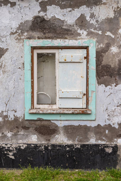A wooden shuttered window on an old stuccoed building.