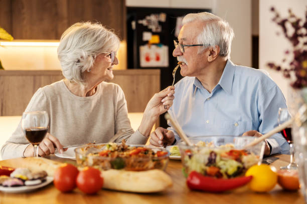 istock A senior woman is feeding her husband at lunch table at home. 2154201701