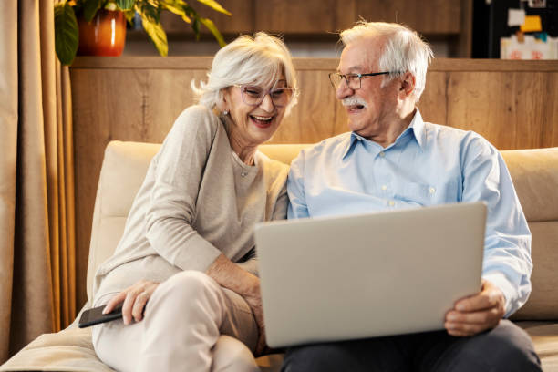 istock A cheerful senior couple is sitting at home and using laptop. 2154201753