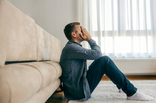 istock A depressed man is sitting on the floor in despair. 2154201870