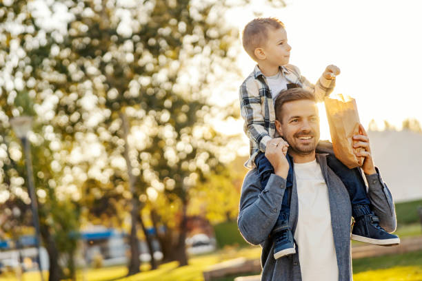 istock A loving father is having piggyback ride with his son in a park. 2154202482