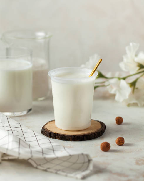 istock Fresh yogurt in a plastic cup with a golden spoon on a rustic wooden coaster. Dairy product 2154205917