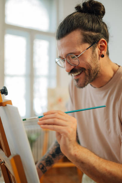 istock Smiling artistic painter painting on easel at creative art studio. 2154211904
