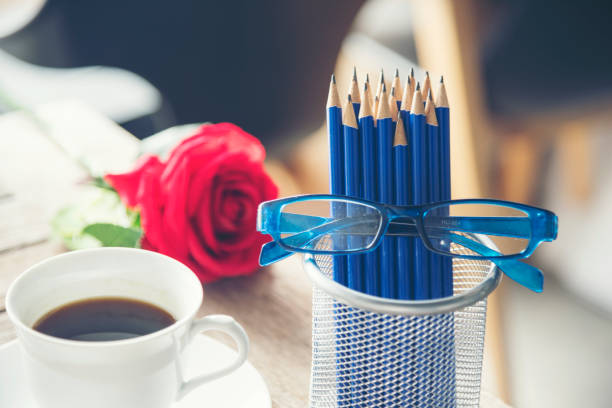 Sharp HB blue pencil silver vase office supply decor coffee cup roses on wood table. Green decorate home office desk. Wood office desk sharpen blue 2B pencil box home office decorate table