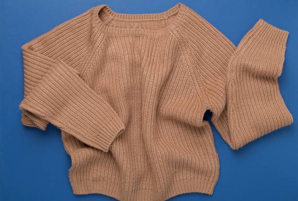 istock Beige knitted sweater on color background, top view 2154219842