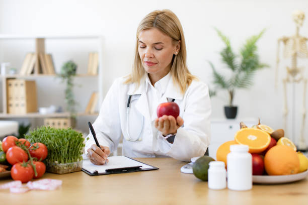 istock Portrait of female posing with apple while doing paperwork in doctor's office. 2154220261