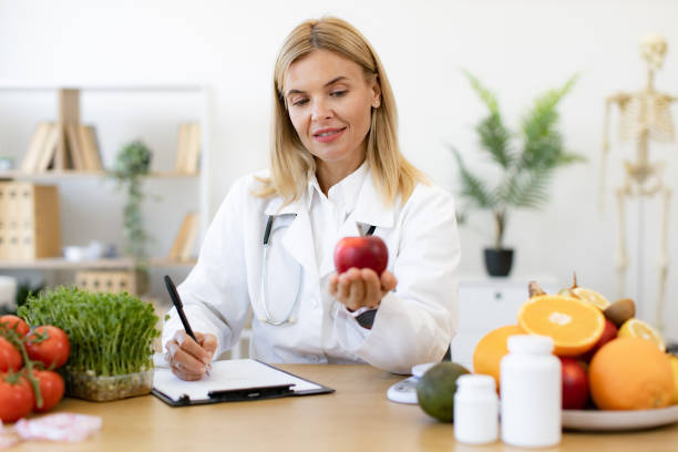 istock Portrait of female posing with apple while doing paperwork in doctor's office. 2154220266