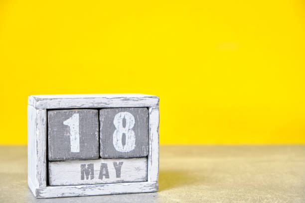 istock May 18 calendar made wooden cubes yellow background.With an empty space for your text. 2154223263