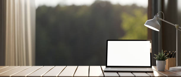 istock A laptop computer mockup and accessories on a wooden tabletop against the window with a nature view. 2154226918